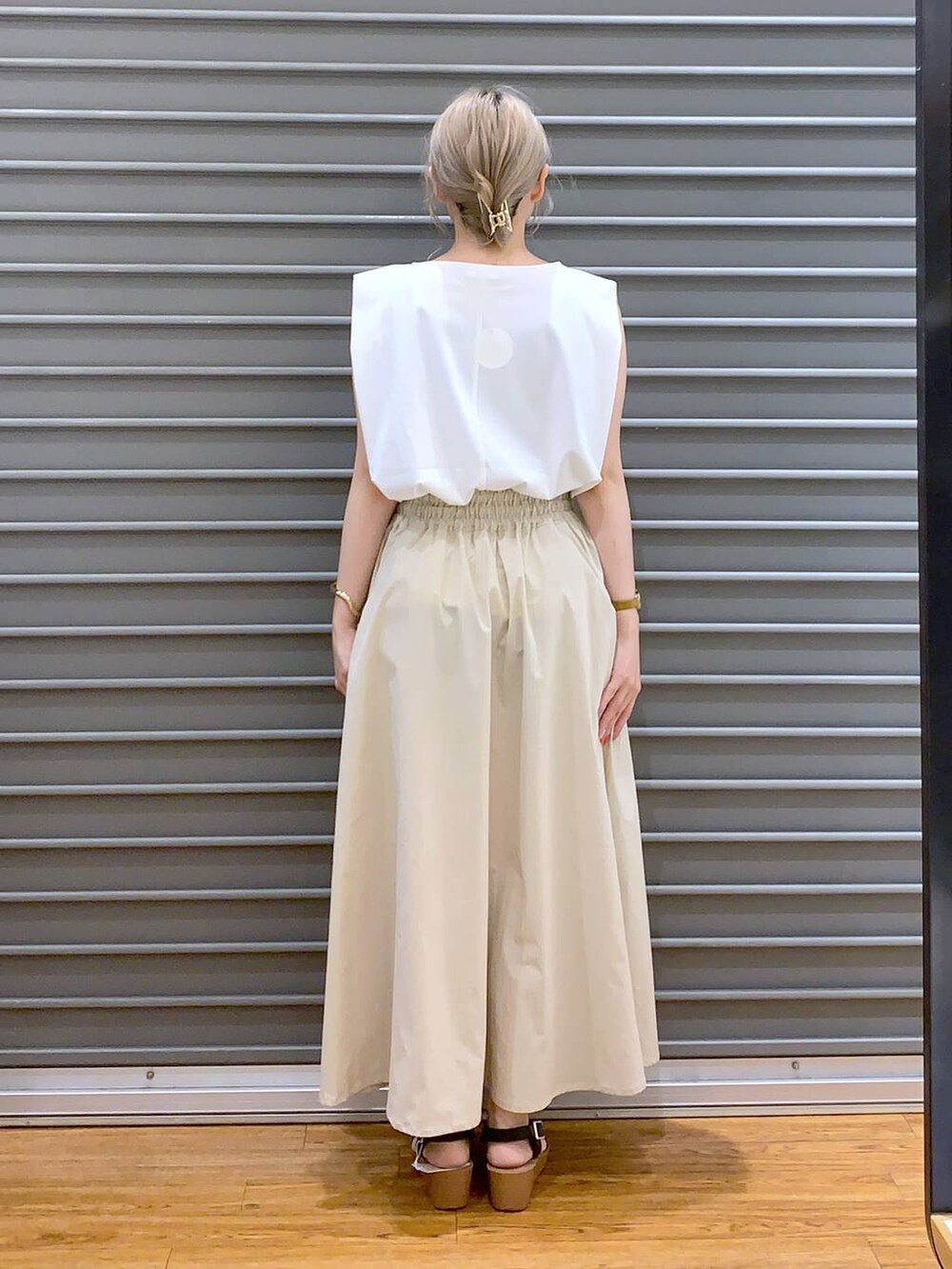 ブラック系のハンドバッグ、ホワイト系のスカート、ブラック系のサンダルを着用したレディースの夏コーディネートの2枚目の写真