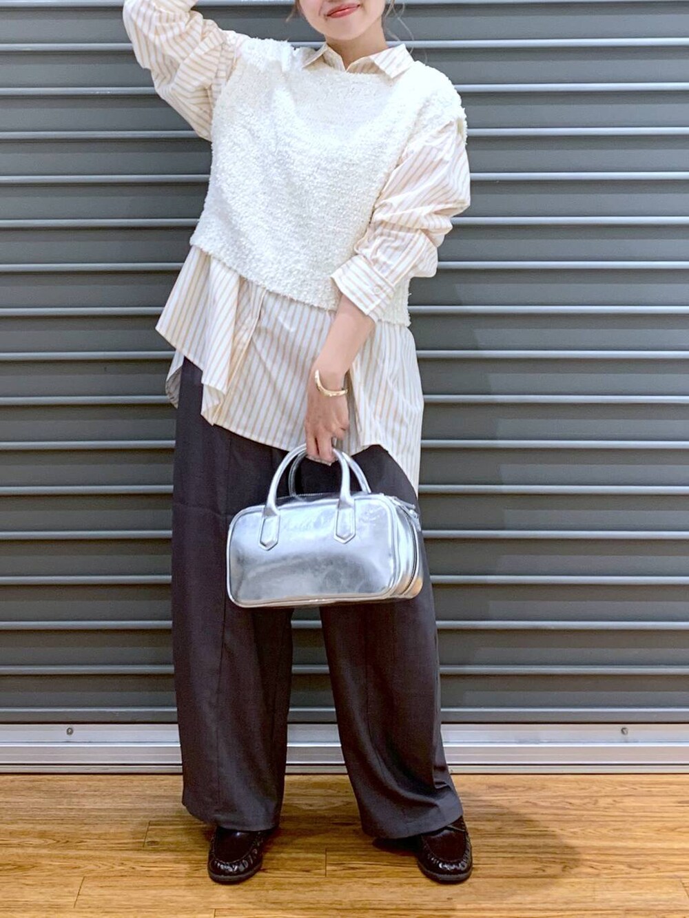 シルバー系のボストンバッグ、ホワイト系のベスト、オレンジ系のシャツ/ブラウスを着用したレディースの秋コーディネートの7枚目の写真