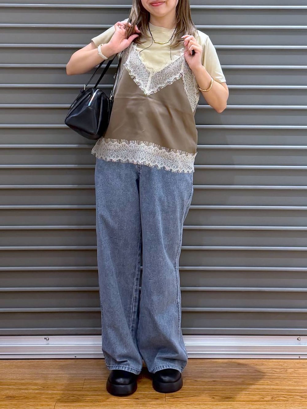 ブラック系のサンダル、ブラック系のボストンバッグ、ブルー系のデニムパンツを着用したレディースの春コーディネートの6枚目の写真