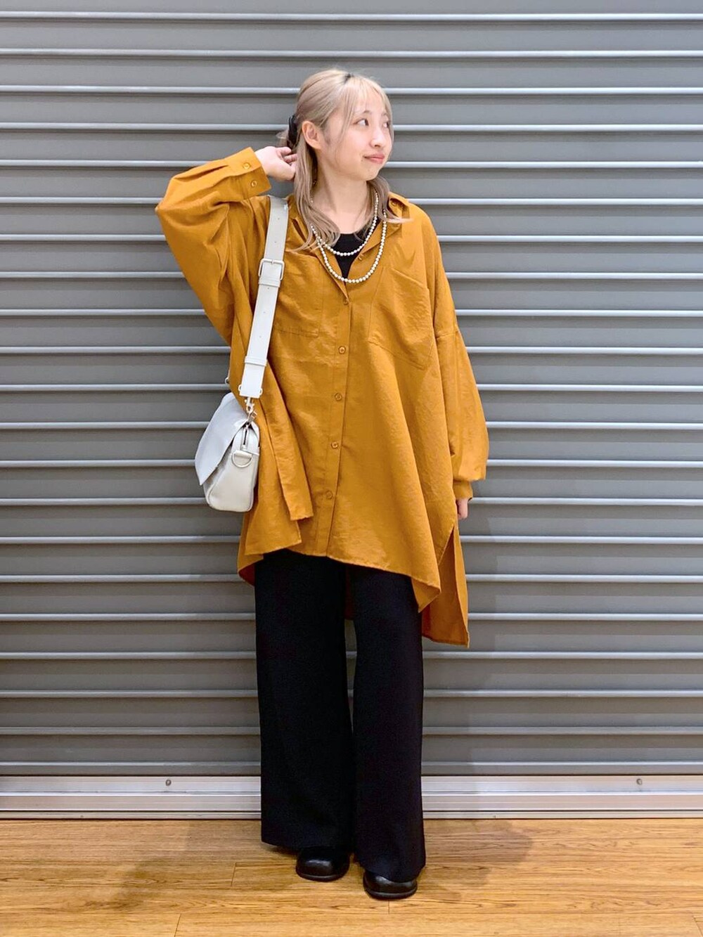 オレンジ系のシャツ/ブラウス、ブラック系のその他パンツ、グレー系のショルダーバッグを着用したレディースの秋コーディネートの5枚目の写真