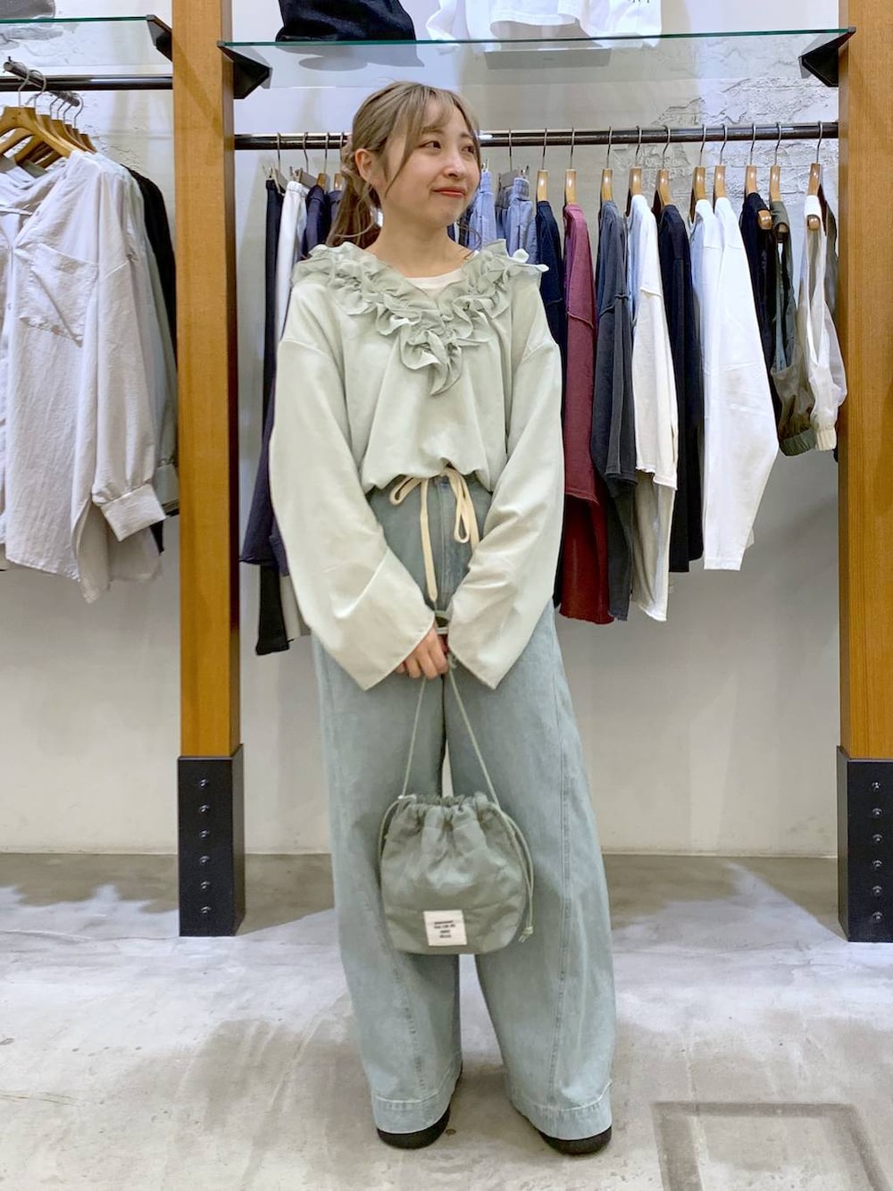 グリーン系のショルダーバッグ、ブルー系のデニムパンツ、ブラック系のサンダルを着用したレディースの春コーディネートの8枚目の写真
