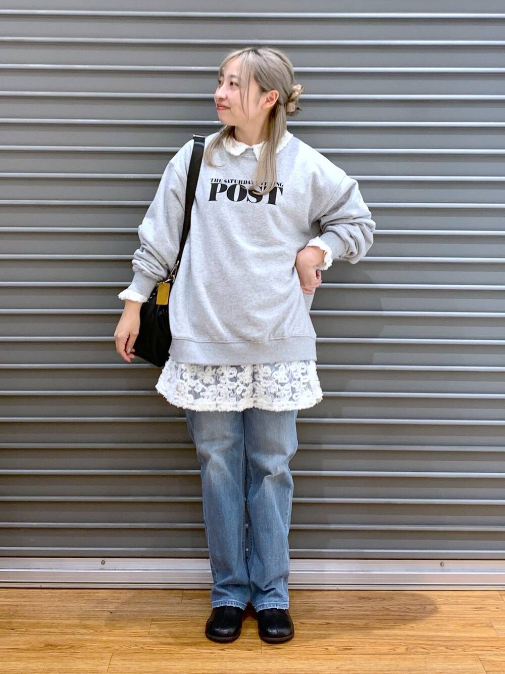 ブラック系のショルダーバッグ、ブルー系のデニムパンツ、ブラック系のブーツを着用したレディースの冬コーディネートの6枚目の写真