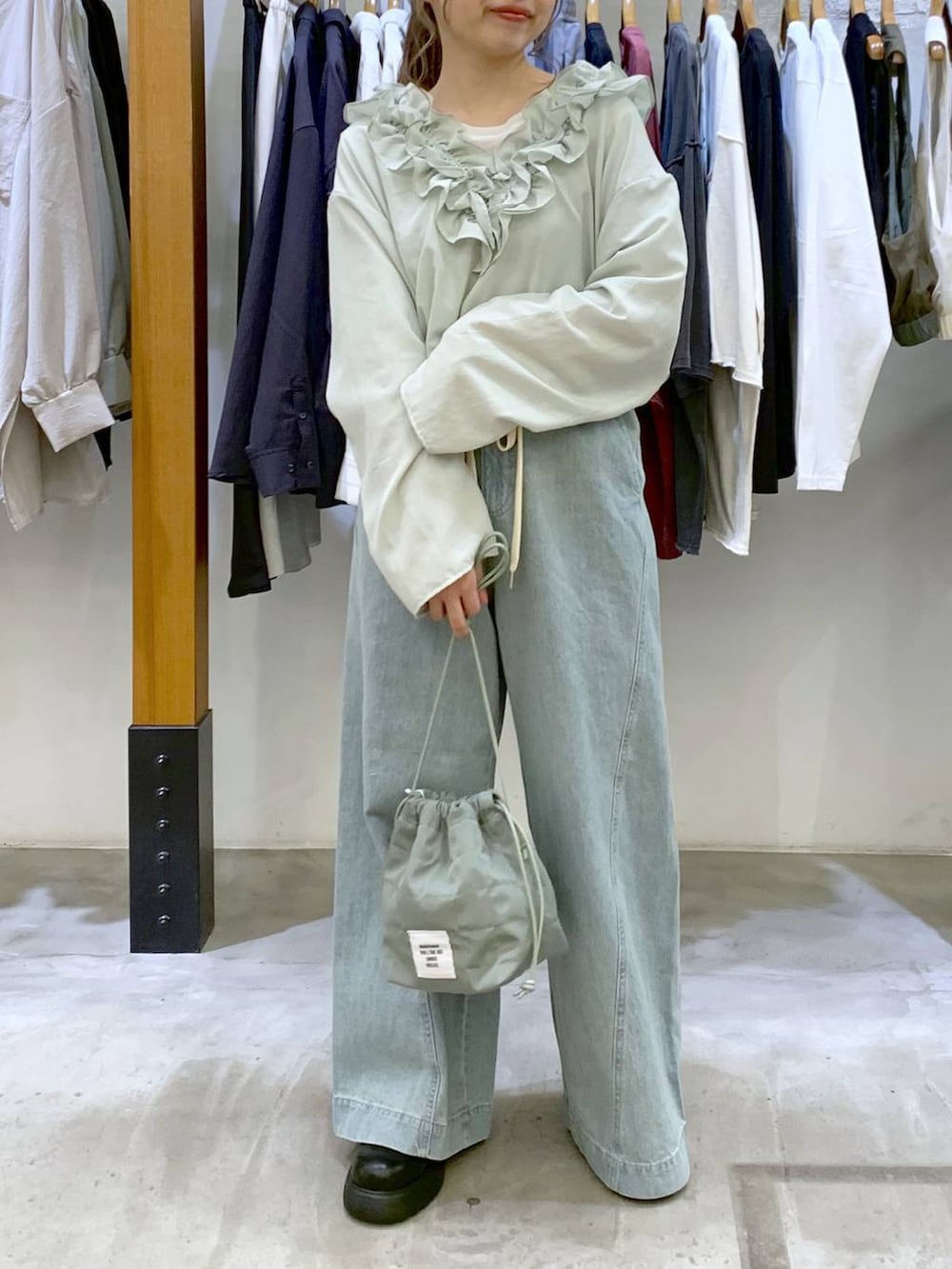 グリーン系のショルダーバッグ、ブルー系のデニムパンツ、ブラック系のサンダルを着用したレディースの春コーディネートの7枚目の写真