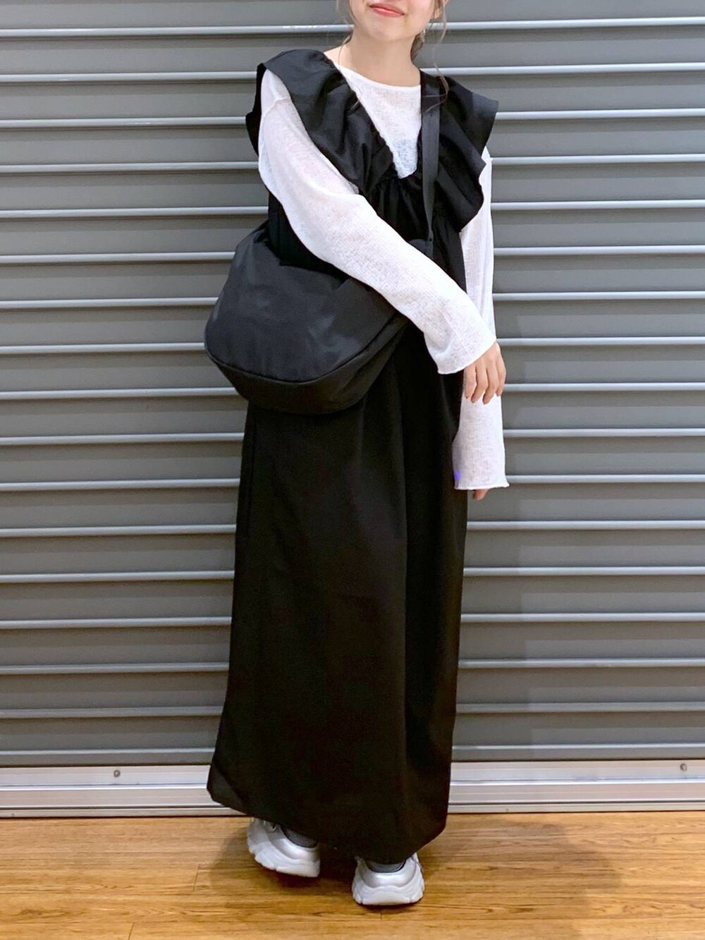 ブラック系のジャンパースカート、シルバー系のスニーカー、ホワイト系のTシャツ/カットソーを着用したレディースの春コーディネートの4枚目の写真
