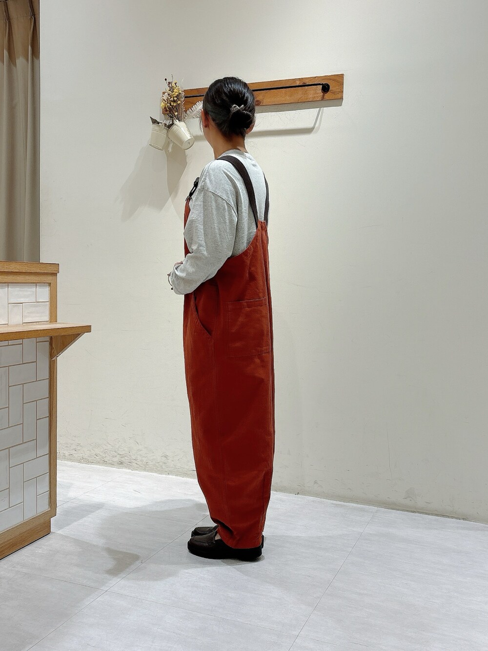 オレンジ系のオールインワン・サロペット、グレー系のTシャツ/カットソー、ブラウン系のドレスシューズを着用したレディースの秋コーディネートの2枚目の写真