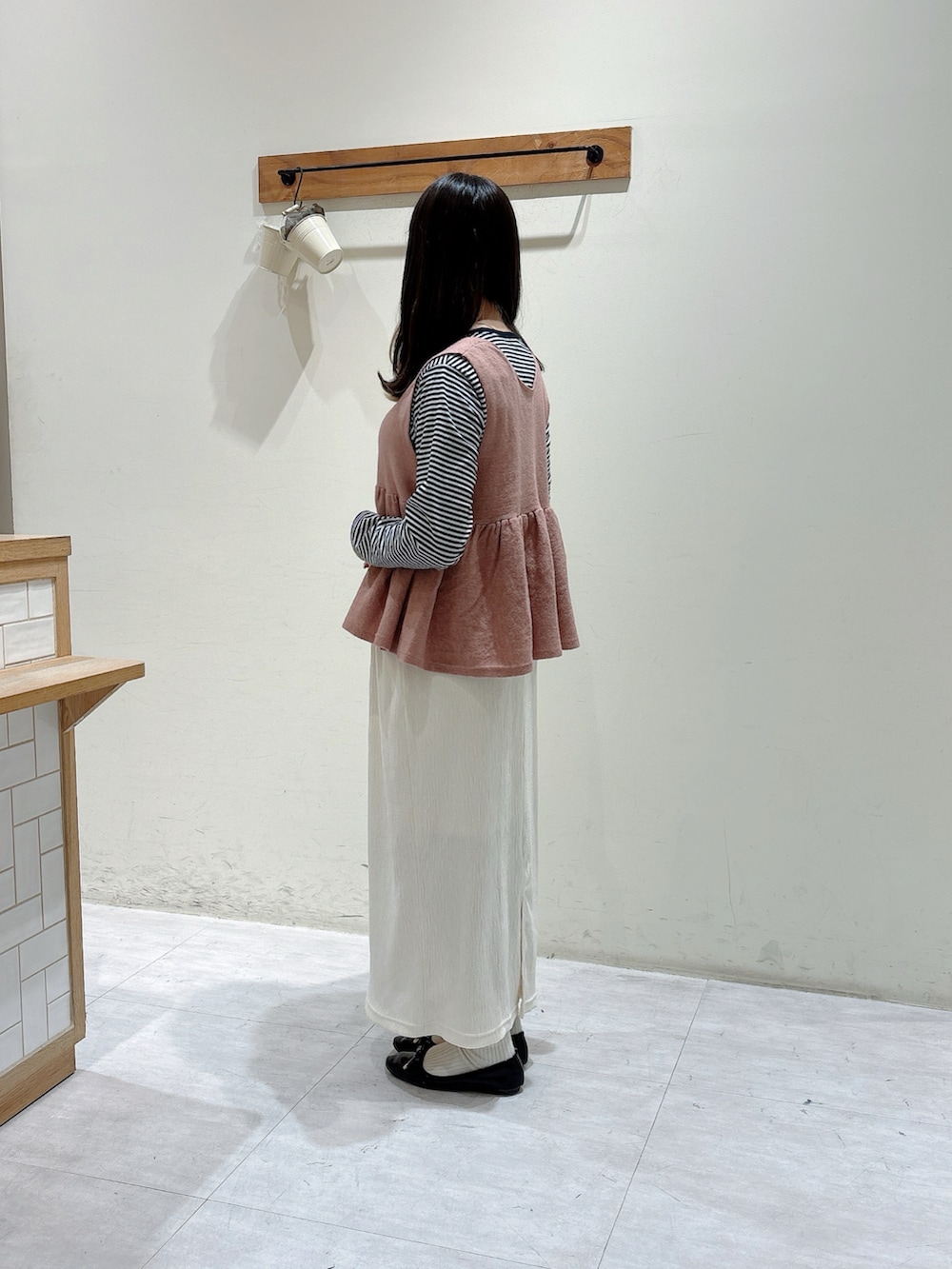 グレー系のTシャツ/カットソー、ピンク系のベスト、ホワイト系のスカートを着用したレディースの冬コーディネートの2枚目の写真