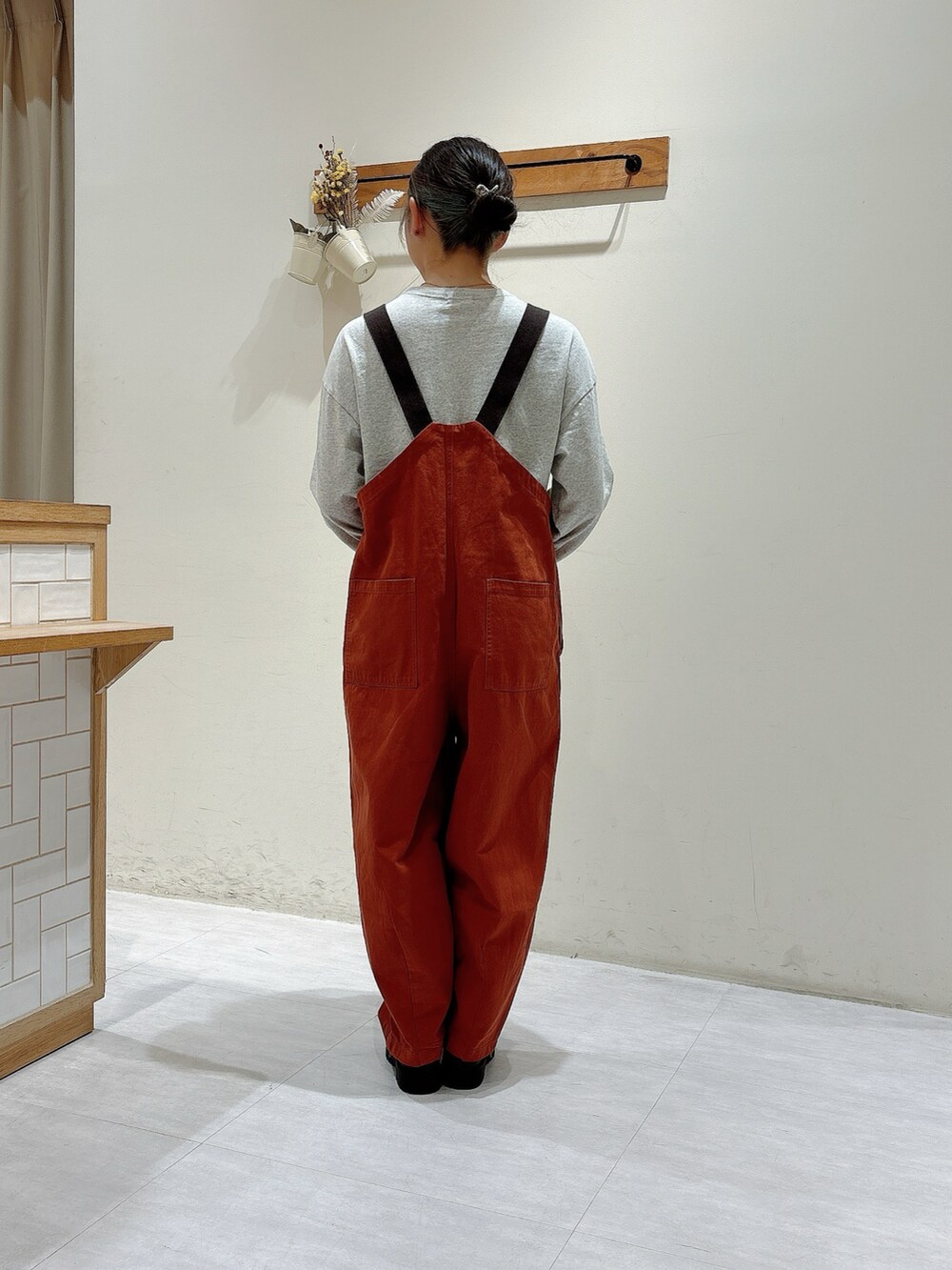 オレンジ系のオールインワン・サロペット、グレー系のTシャツ/カットソー、ブラウン系のドレスシューズを着用したレディースの秋コーディネートの3枚目の写真