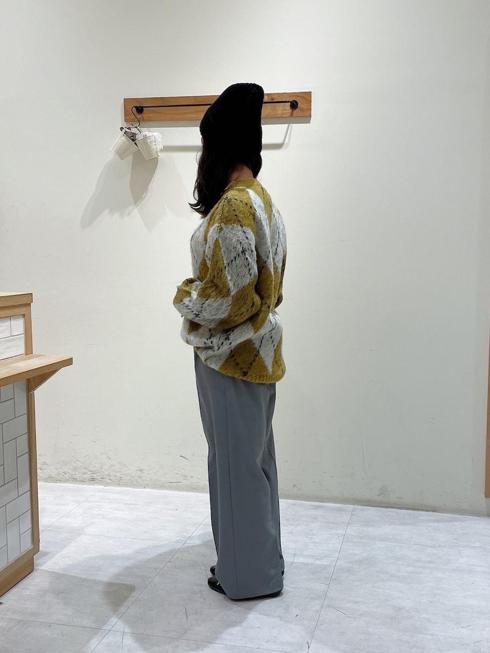 イエロー系のニット/セーター、グレー系のその他パンツ、ブラック系のハットを着用したレディースの冬コーディネートの2枚目の写真