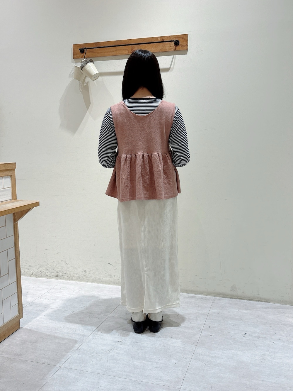 グレー系のTシャツ/カットソー、ピンク系のベスト、ホワイト系のスカートを着用したレディースの冬コーディネートの3枚目の写真