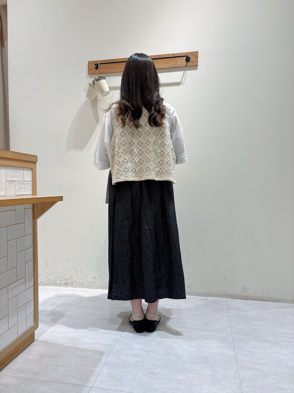 ホワイト系のトップス、ホワイト系のベスト、ブラック系のスカートを着用したレディースの春コーディネートの3枚目の写真