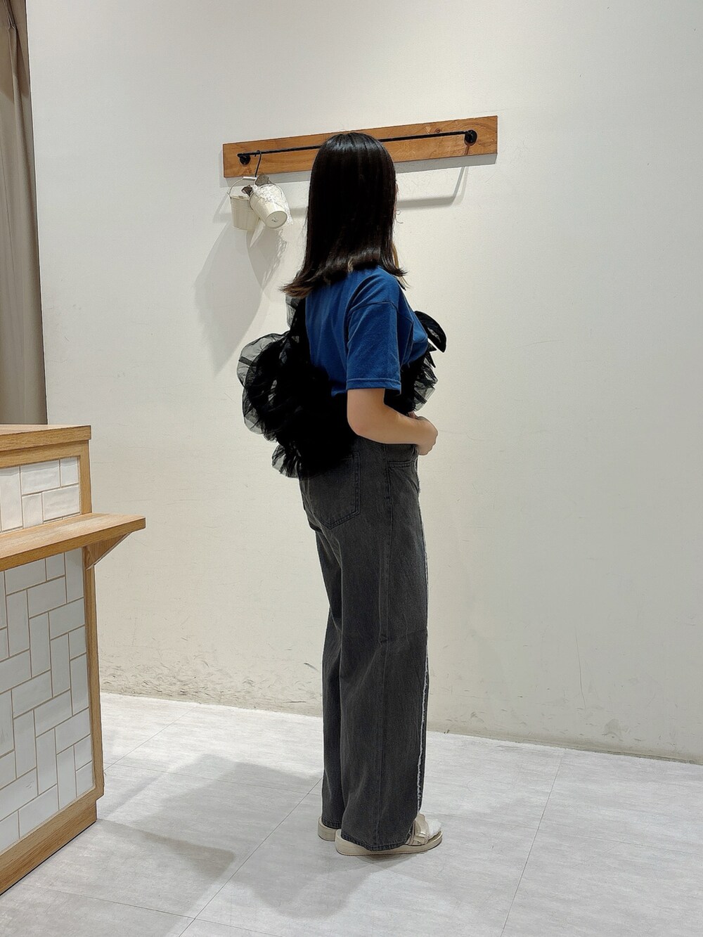 グレー系のパンツ、ブラック系のハンドバッグ、ブルー系のTシャツ/カットソーを着用したレディースの夏コーディネートの2枚目の写真