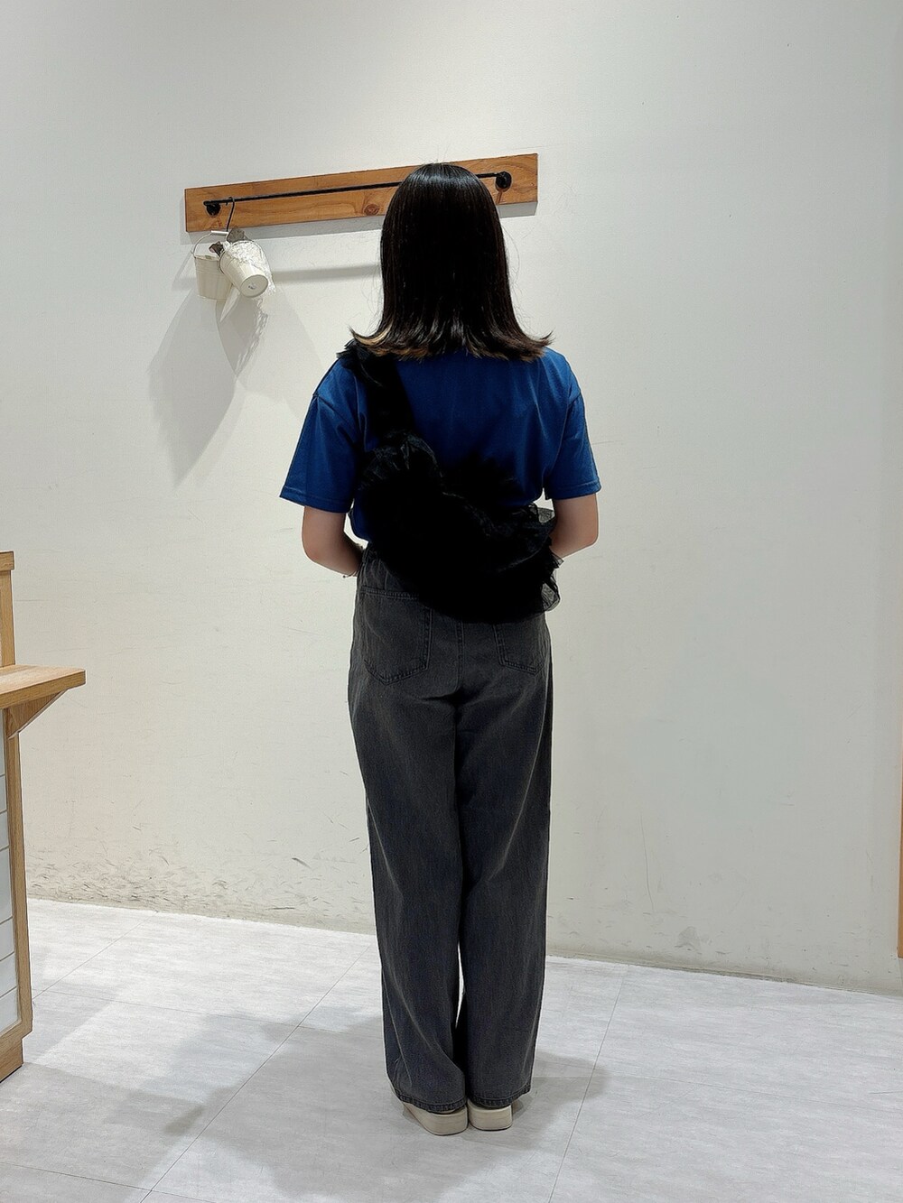 グレー系のパンツ、ブラック系のハンドバッグ、ブルー系のTシャツ/カットソーを着用したレディースの夏コーディネートの3枚目の写真