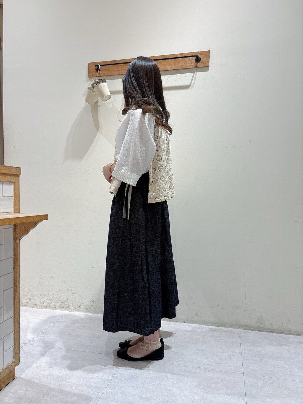 ホワイト系のトップス、ホワイト系のベスト、ブラック系のスカートを着用したレディースの春コーディネートの2枚目の写真