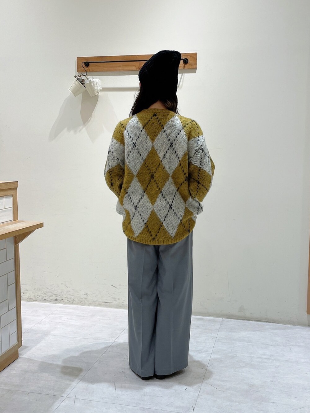 イエロー系のニット/セーター、グレー系のその他パンツ、ブラック系のハットを着用したレディースの冬コーディネートの3枚目の写真