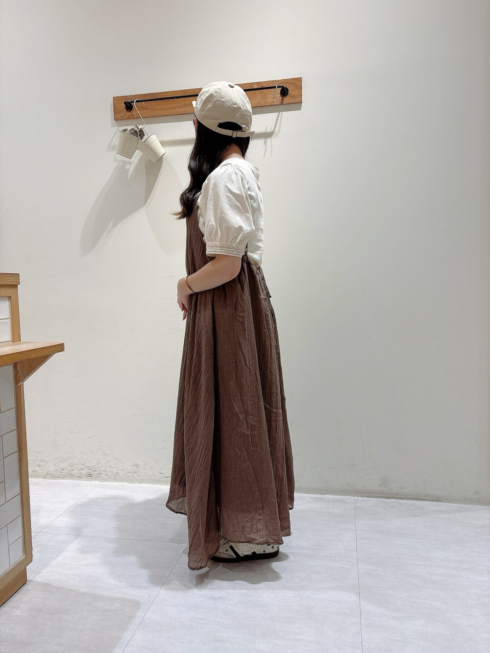 ブラウン系のワンピース、ホワイト系のTシャツ/カットソー、ベージュ系のハットを着用したレディースの夏コーディネートの2枚目の写真