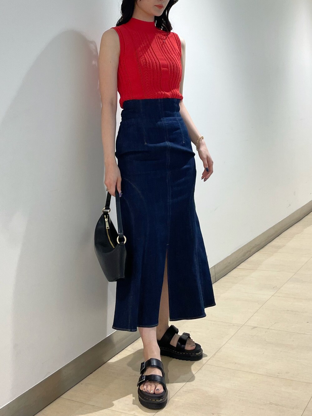 ブラック系のハンドバッグ、レッド系のニット/セーター、ブルー系のデニムスカートを着用したレディースの夏コーディネートの4枚目の写真