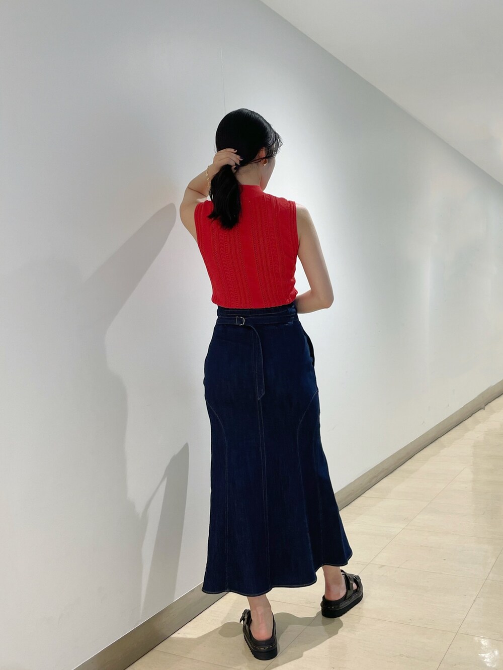 ブラック系のハンドバッグ、レッド系のニット/セーター、ブルー系のデニムスカートを着用したレディースの夏コーディネートの3枚目の写真