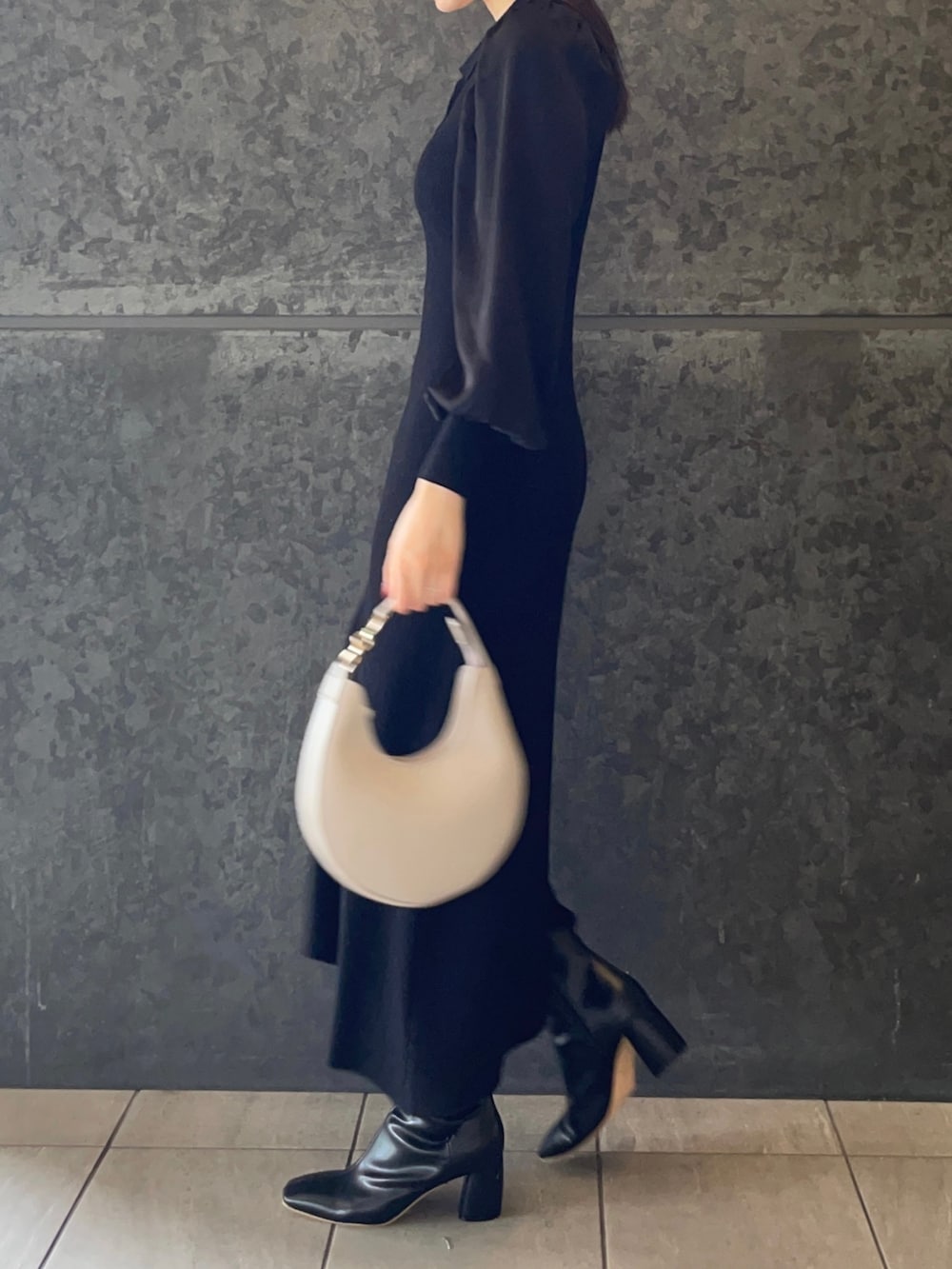 ホワイト系のハンドバッグ、ブラック系のブーツ、ブラック系のワンピースを着用したレディースの秋コーディネートの3枚目の写真