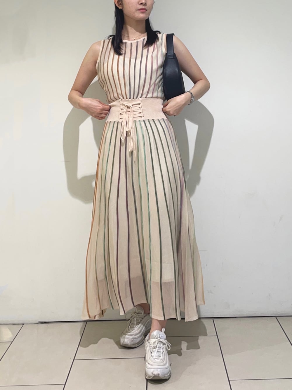 ホワイト系のワンピース、ブラック系のハンドバッグを着用したレディースの春コーディネートの2枚目の写真