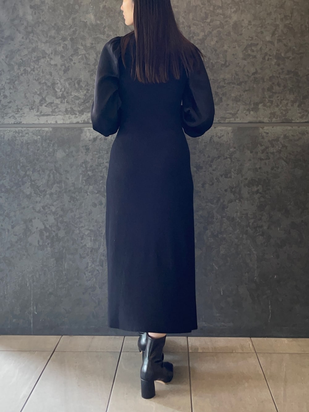 ホワイト系のハンドバッグ、ブラック系のブーツ、ブラック系のワンピースを着用したレディースの秋コーディネートの4枚目の写真