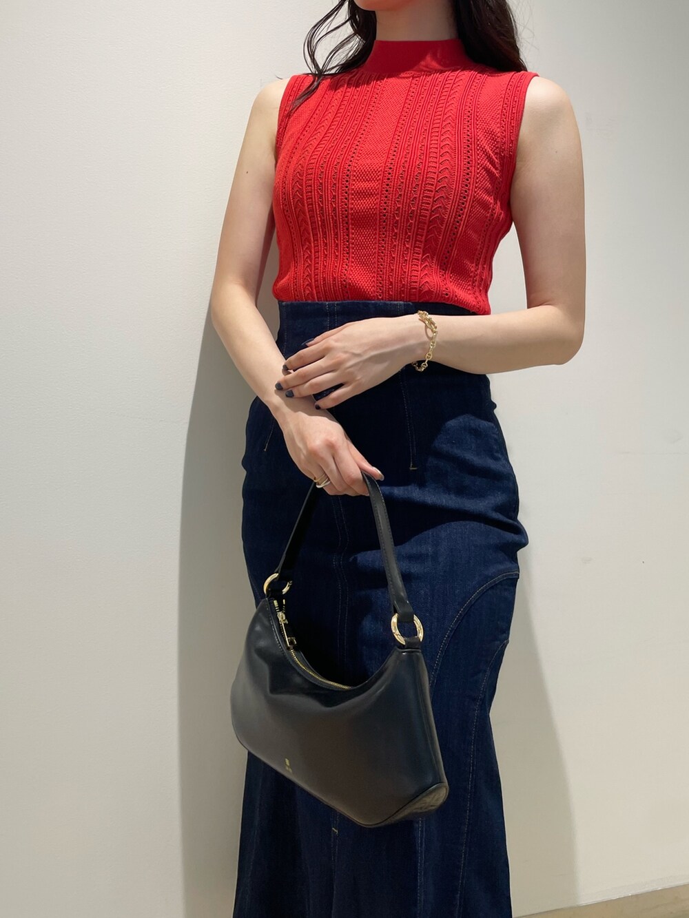 ブラック系のハンドバッグ、レッド系のニット/セーター、ブルー系のデニムスカートを着用したレディースの夏コーディネートの5枚目の写真