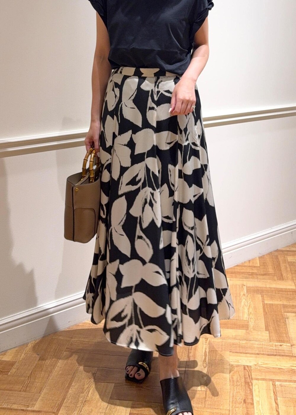 ブラック系のサンダル、ベージュ系のハンドバッグ、ブラック系のTシャツ/カットソーを着用したレディースの夏コーディネートの4枚目の写真