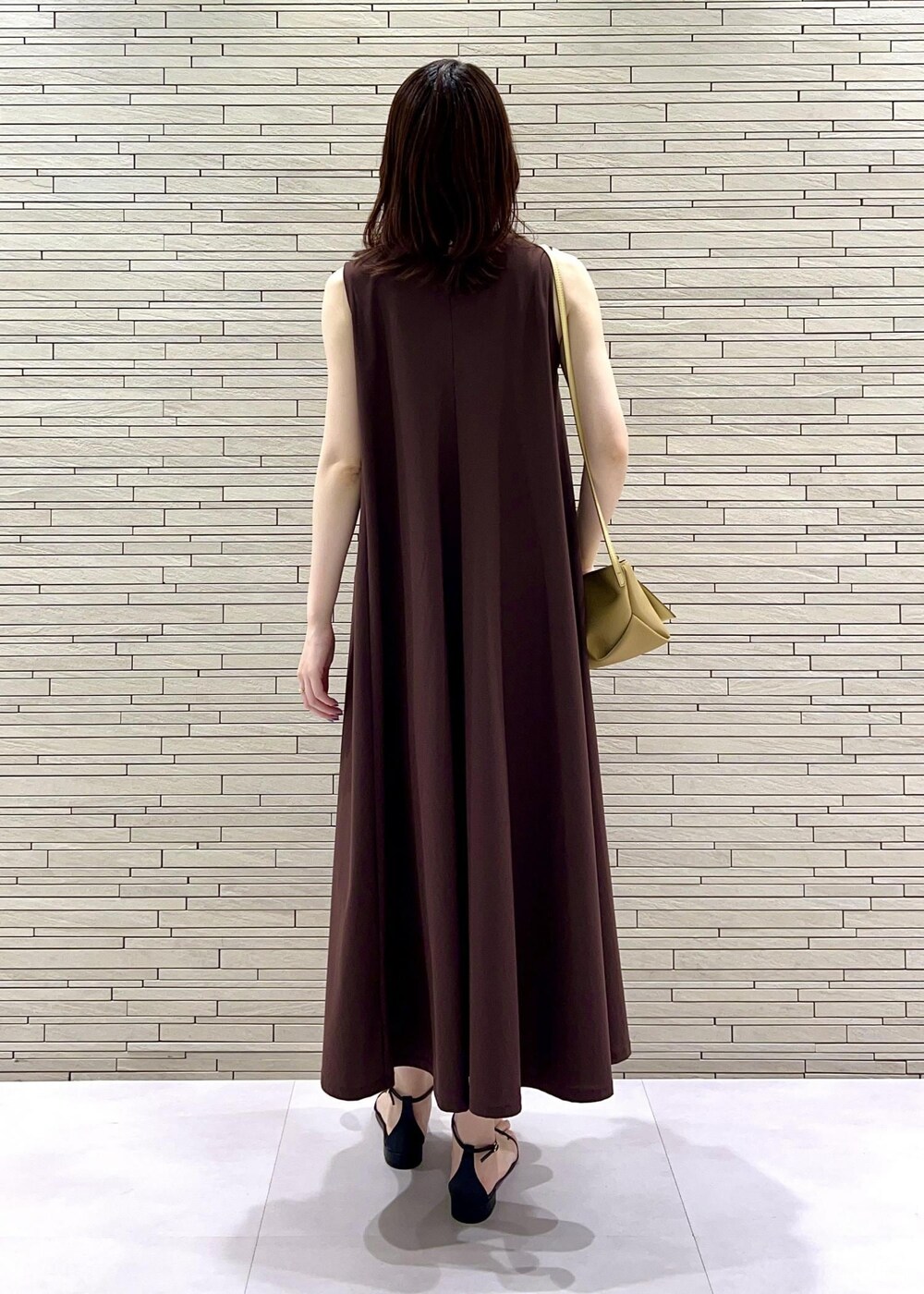 イエロー系のショルダーバッグ、ブラック系のサンダル、ブラウン系のワンピースを着用したレディースの夏コーディネートの2枚目の写真