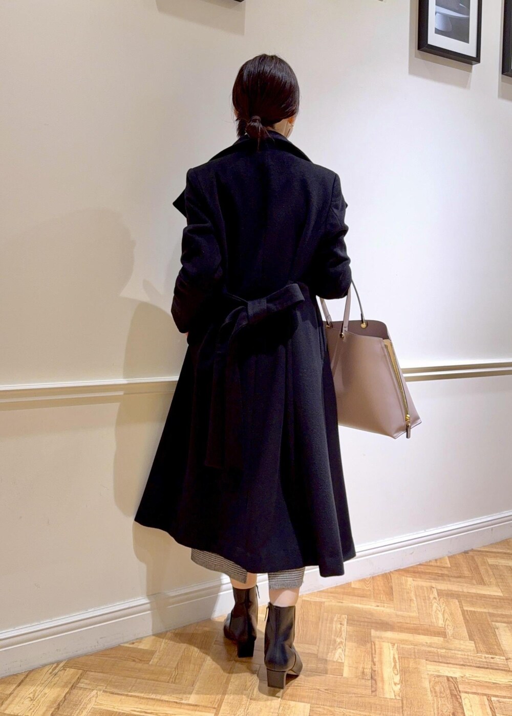 ブラック系のブーツ、グレー系のトートバッグ、ブラック系のステンカラーコートを着用したレディースの秋コーディネートの2枚目の写真