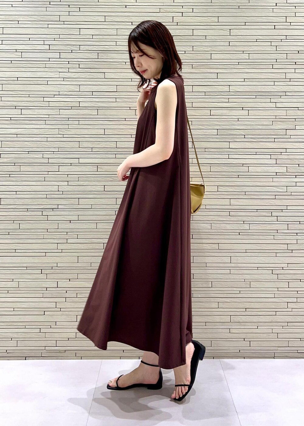 イエロー系のショルダーバッグ、ブラック系のサンダル、ブラウン系のワンピースを着用したレディースの夏コーディネートの3枚目の写真