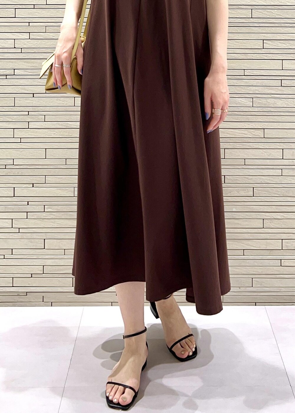 イエロー系のショルダーバッグ、ブラック系のサンダル、ブラウン系のワンピースを着用したレディースの夏コーディネートの7枚目の写真