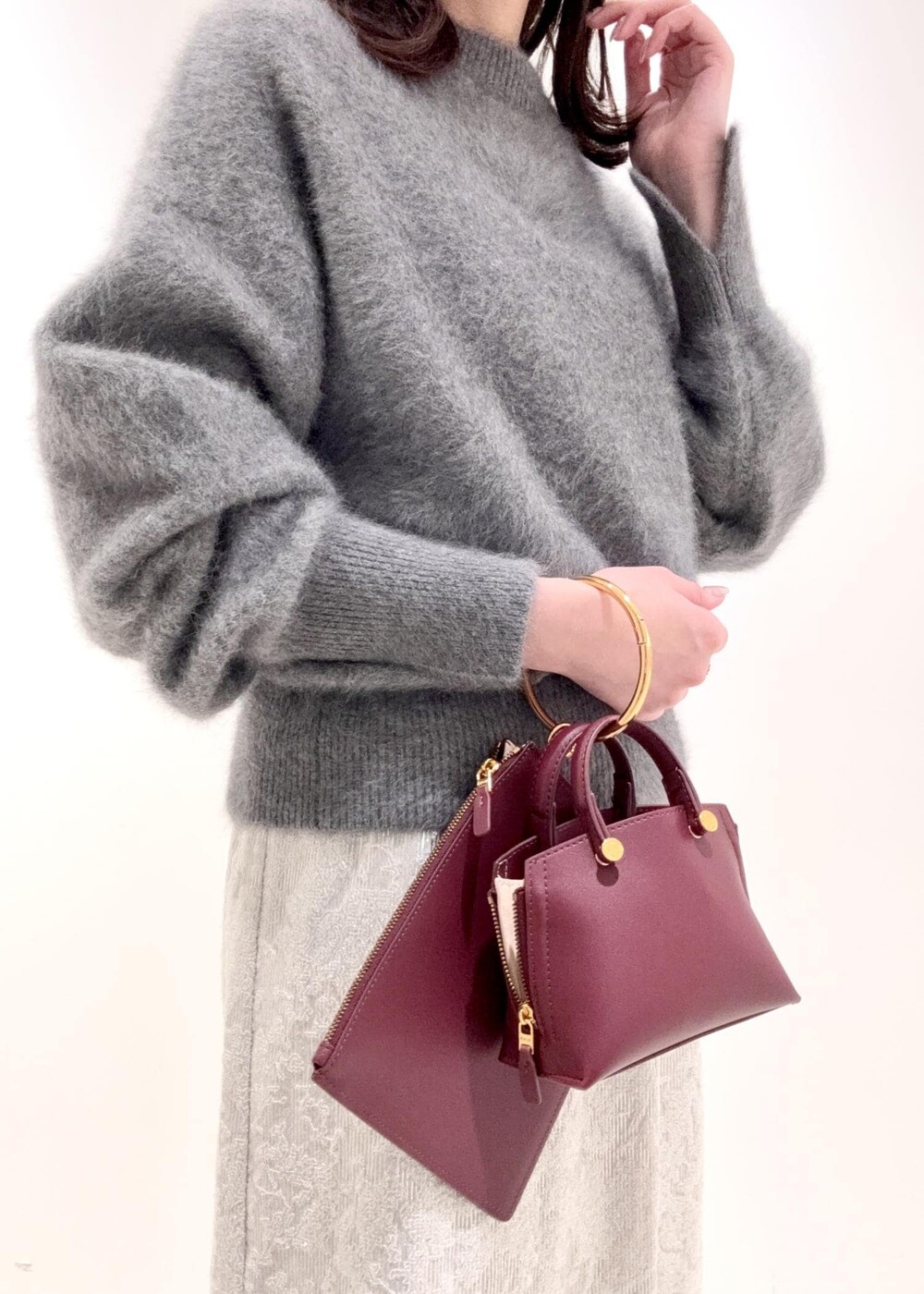 レッド系のショルダーバッグ、ブラック系のブーツ、グレー系のニット/セーターを着用したレディースの冬コーディネートの8枚目の写真