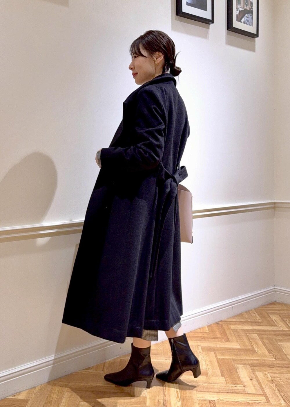 ブラック系のブーツ、グレー系のトートバッグ、ブラック系のステンカラーコートを着用したレディースの秋コーディネートの3枚目の写真