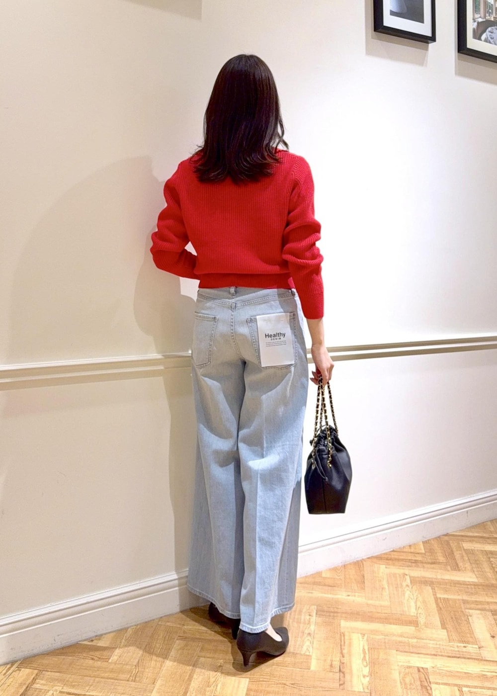 ブラック系のハンドバッグ、レッド系のニット/セーター、ブルー系のデニムパンツを着用したレディースの冬コーディネートの2枚目の写真