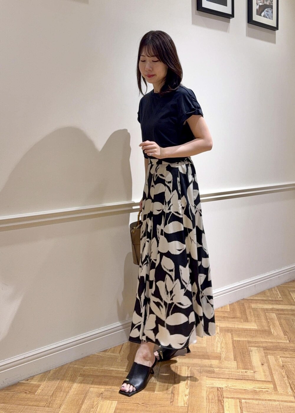 ブラック系のサンダル、ベージュ系のハンドバッグ、ブラック系のTシャツ/カットソーを着用したレディースの夏コーディネートの3枚目の写真