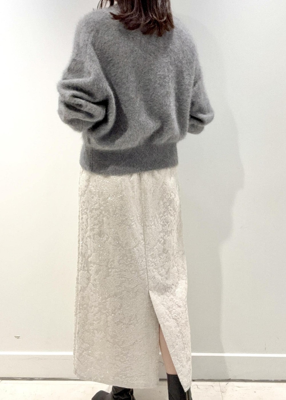 レッド系のショルダーバッグ、ブラック系のブーツ、グレー系のニット/セーターを着用したレディースの冬コーディネートの5枚目の写真