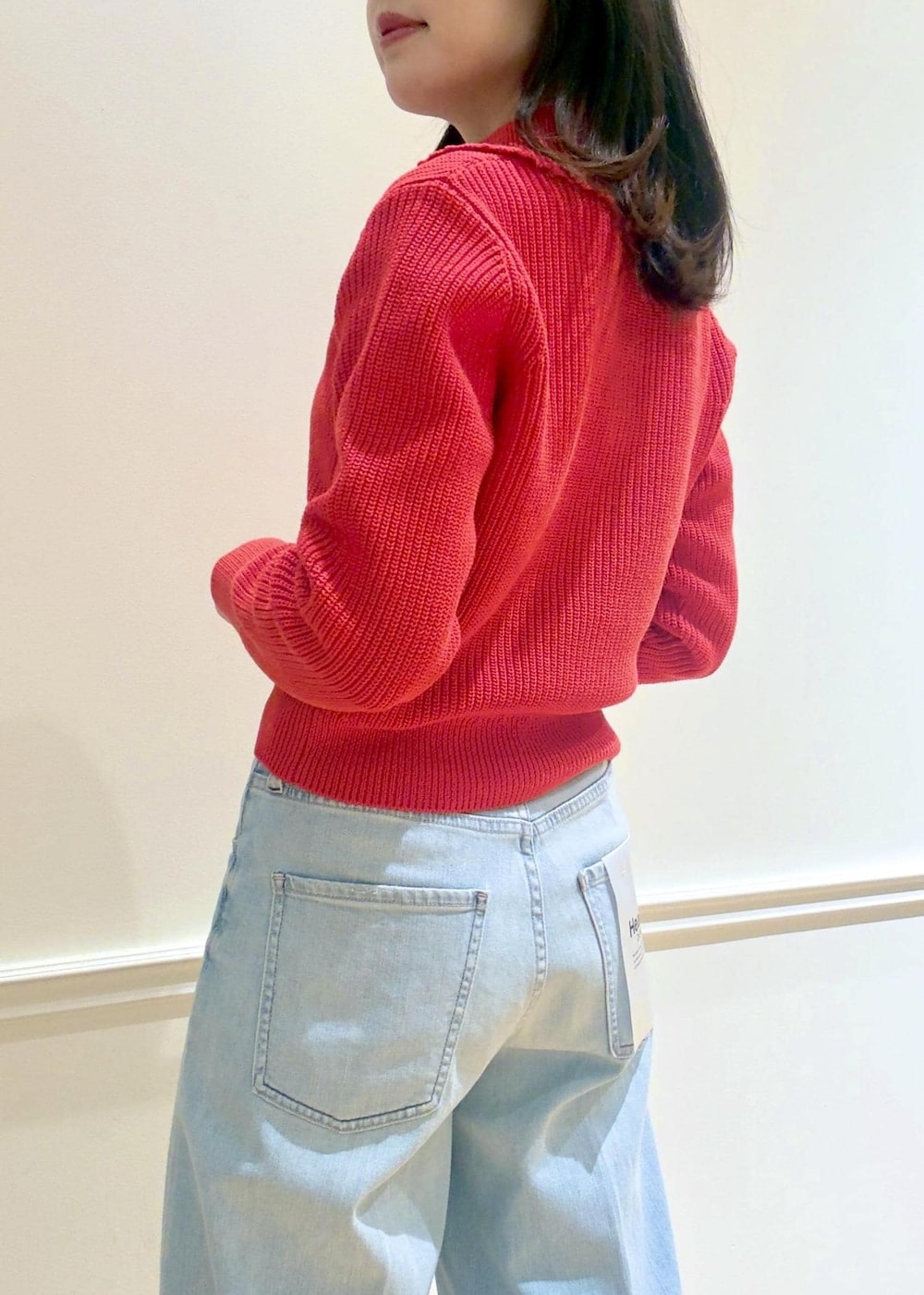 ブラック系のハンドバッグ、レッド系のニット/セーター、ブルー系のデニムパンツを着用したレディースの冬コーディネートの8枚目の写真