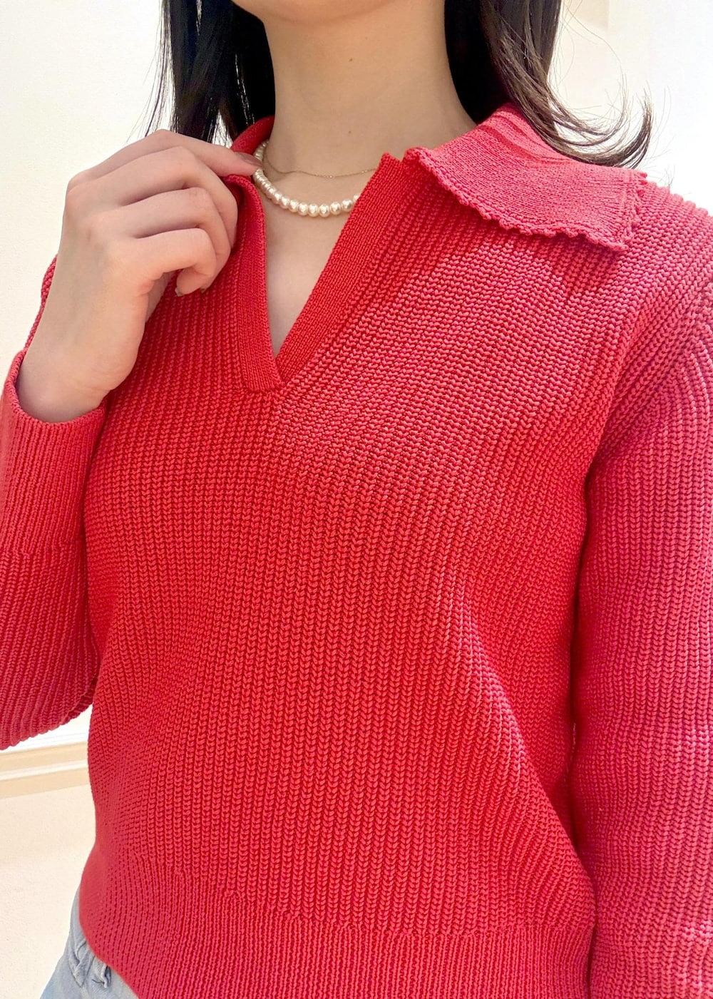 ブラック系のハンドバッグ、レッド系のニット/セーター、ブルー系のデニムパンツを着用したレディースの冬コーディネートの7枚目の写真