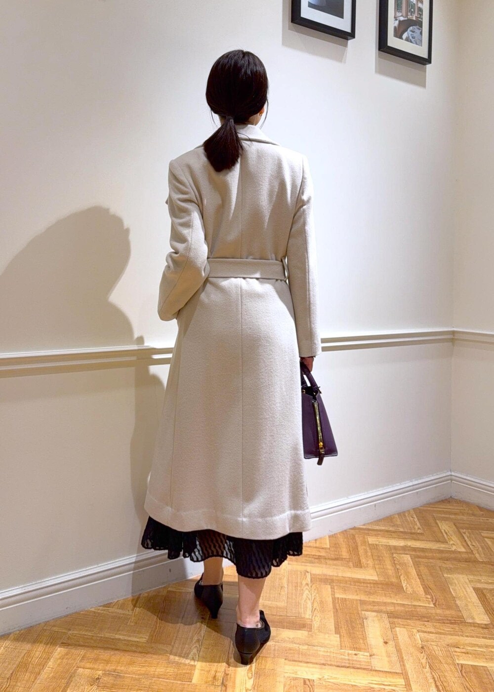 ブラック系のパンプス、パープル系のハンドバッグ、ホワイト系のステンカラーコートを着用したレディースの秋コーディネートの2枚目の写真