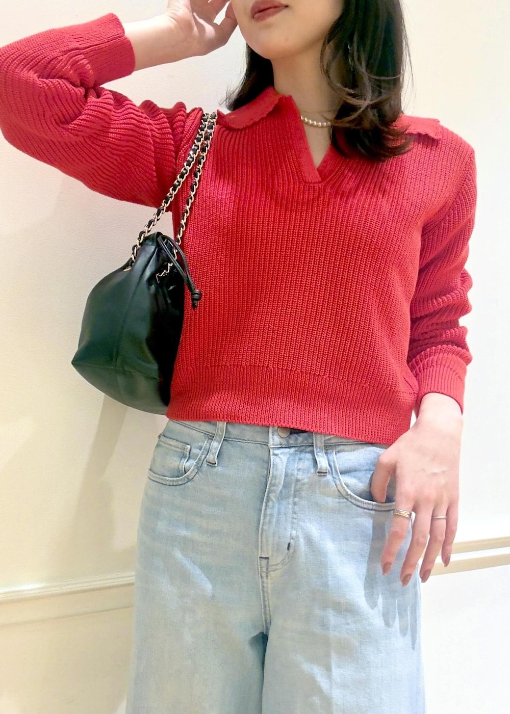 ブラック系のハンドバッグ、レッド系のニット/セーター、ブルー系のデニムパンツを着用したレディースの冬コーディネートの5枚目の写真