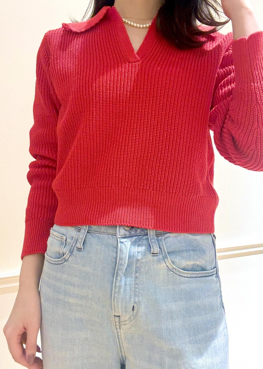 ブラック系のハンドバッグ、レッド系のニット/セーター、ブルー系のデニムパンツを着用したレディースの冬コーディネートの6枚目の写真