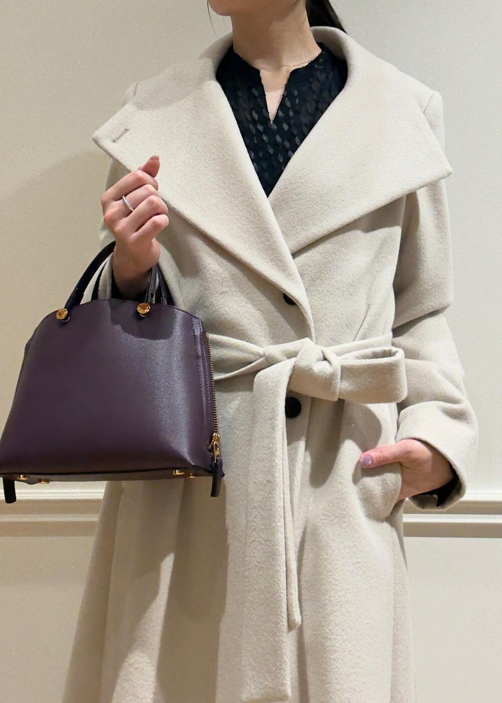 ブラック系のパンプス、パープル系のハンドバッグ、ホワイト系のステンカラーコートを着用したレディースの秋コーディネートの4枚目の写真