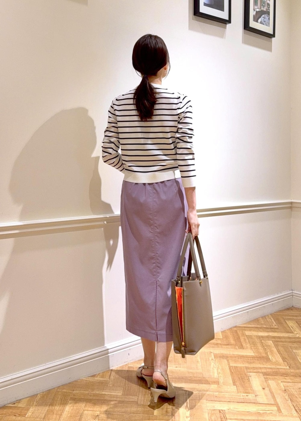 パープル系のスカート、ブラウン系のトートバッグ、ホワイト系のカーディガン/ボレロを着用したレディースの春コーディネートの2枚目の写真