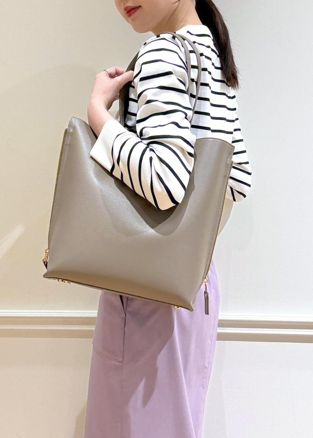 パープル系のスカート、ブラウン系のトートバッグ、ホワイト系のカーディガン/ボレロを着用したレディースの春コーディネートの5枚目の写真