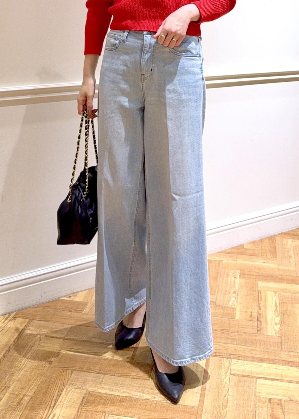 ブラック系のハンドバッグ、レッド系のニット/セーター、ブルー系のデニムパンツを着用したレディースの冬コーディネートの4枚目の写真