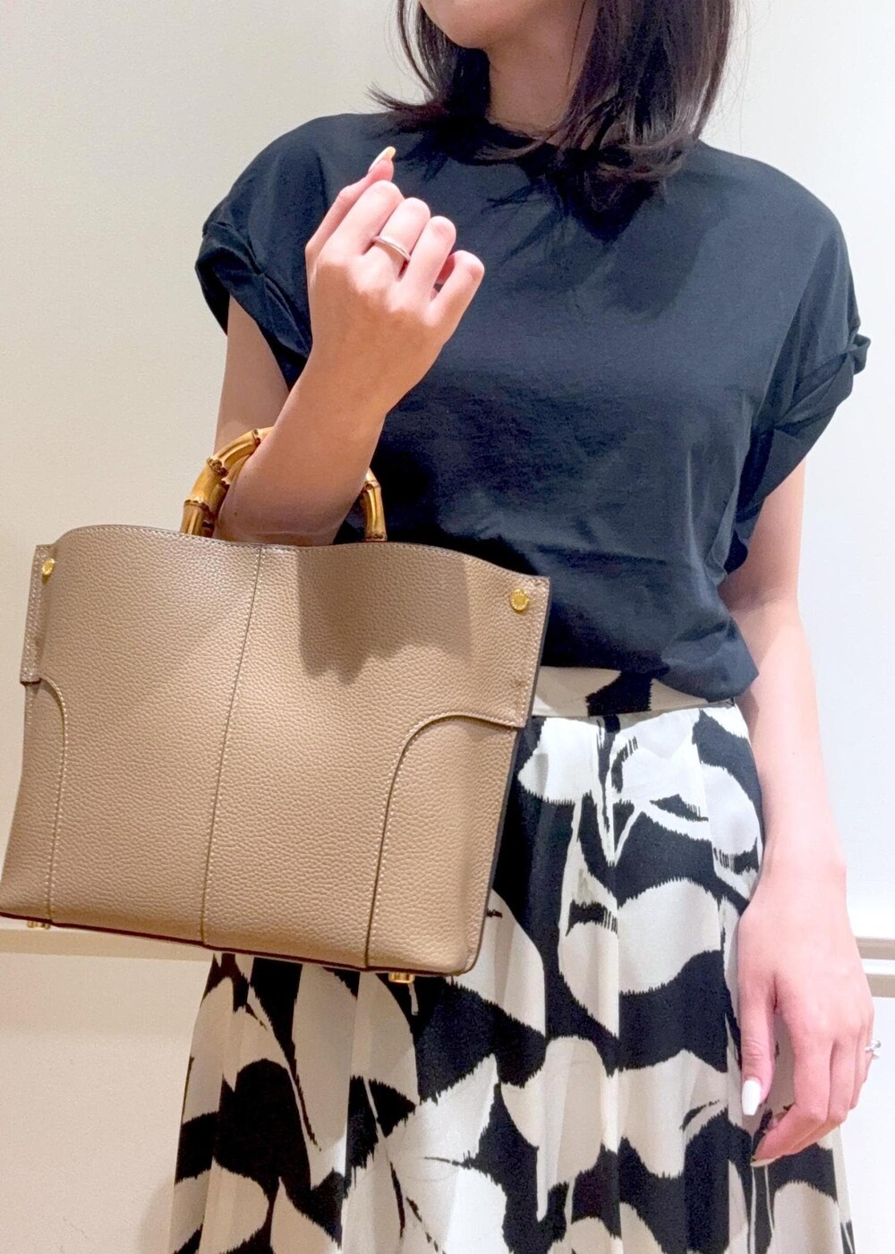 ブラック系のサンダル、ベージュ系のハンドバッグ、ブラック系のTシャツ/カットソーを着用したレディースの夏コーディネートの7枚目の写真