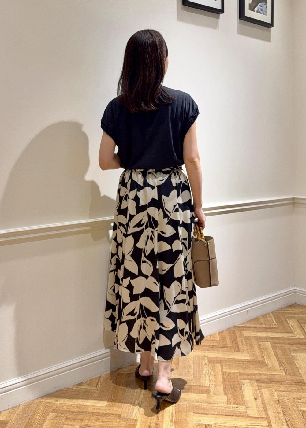 ブラック系のサンダル、ベージュ系のハンドバッグ、ブラック系のTシャツ/カットソーを着用したレディースの夏コーディネートの2枚目の写真