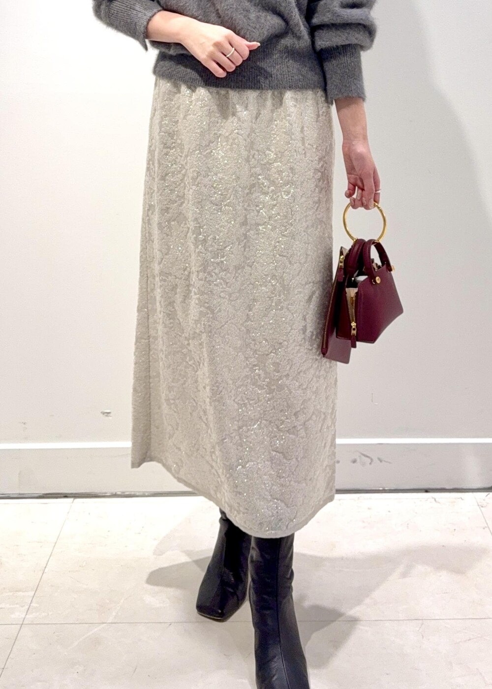 レッド系のショルダーバッグ、ブラック系のブーツ、グレー系のニット/セーターを着用したレディースの冬コーディネートの4枚目の写真