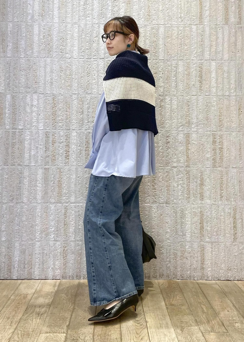 ブルー系のデニムパンツ、ブラック系のパンプス、ブラック系のハンドバッグを着用したレディースの春コーディネートの2枚目の写真