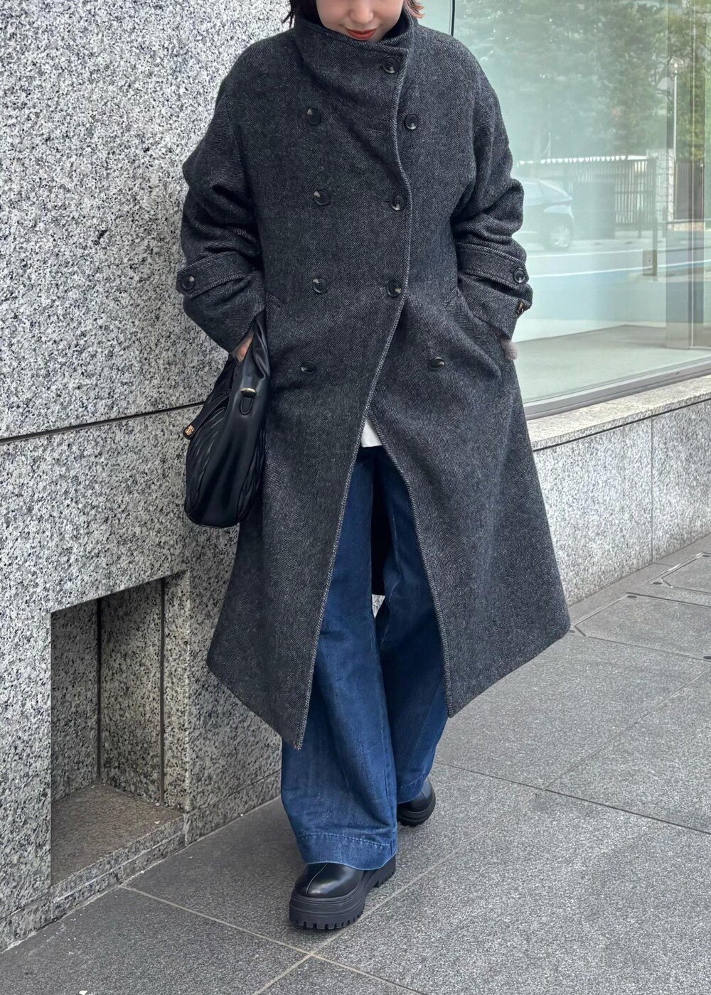 ブルー系のデニムパンツ、ブラック系のブーツ、ブラック系のハンドバッグを着用したレディースの秋コーディネートの4枚目の写真