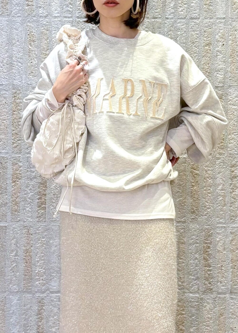 ホワイト系のブーツ、ベージュ系のスカート、ホワイト系のTシャツ/カットソーを着用したレディースの冬コーディネートの2枚目の写真
